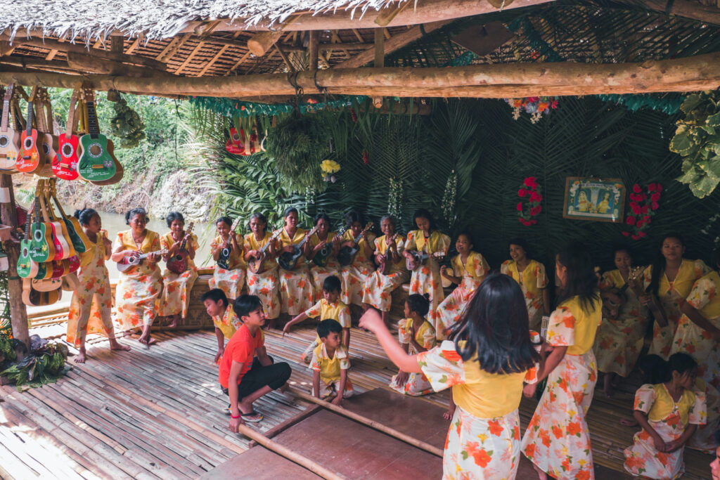 indigenous people singing together under straw thatched roof